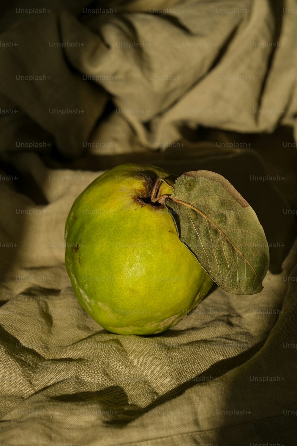 una manzana verde con una hoja encima