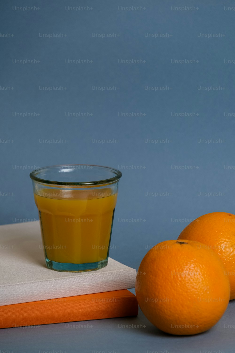 ein Glas Orangensaft neben drei Orangen