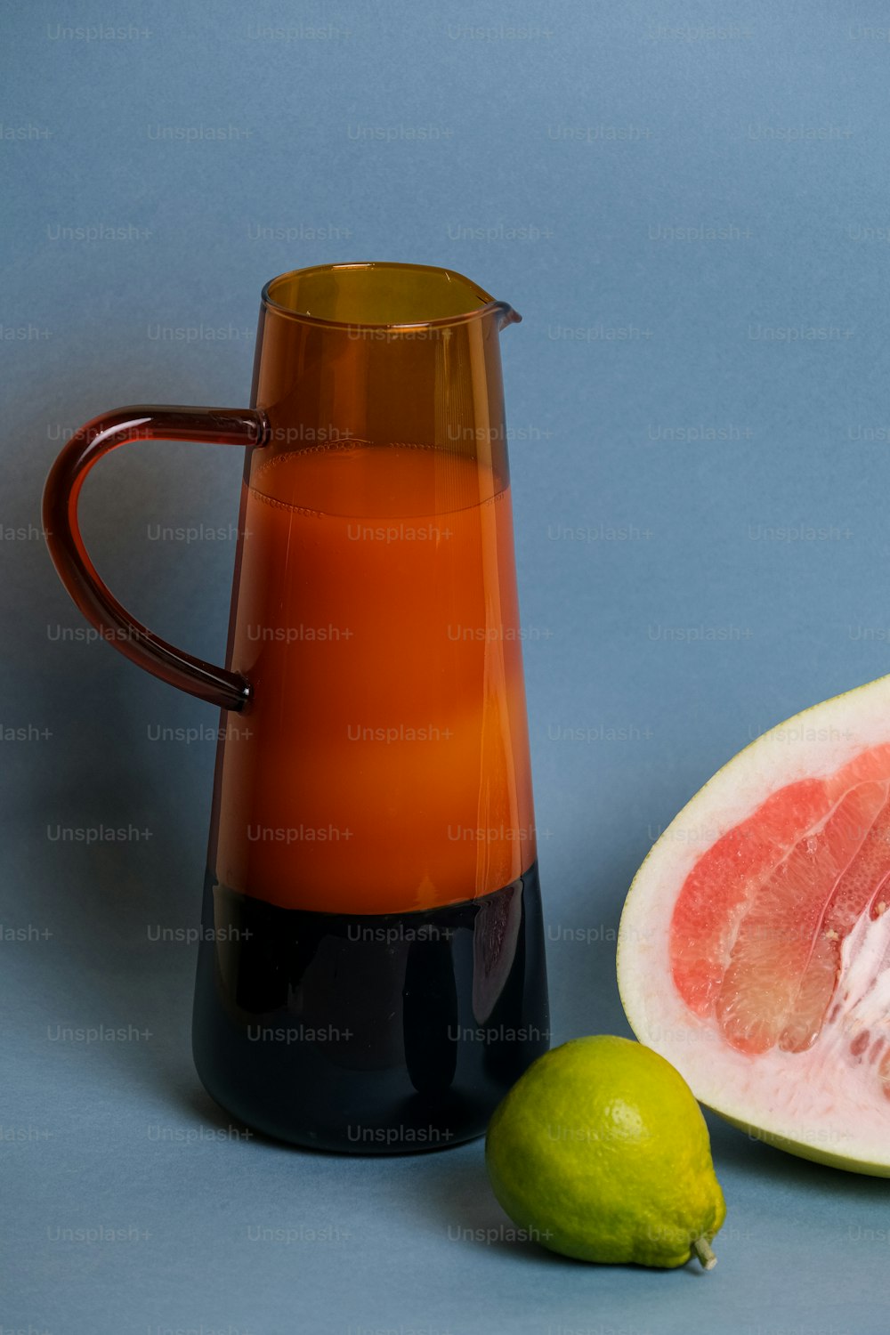 una jarra de líquido junto a la mitad de un pomelo