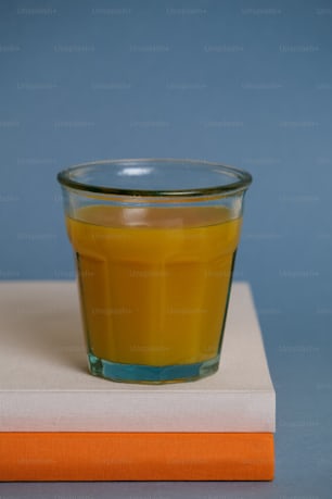 a glass of orange juice sitting on top of a book