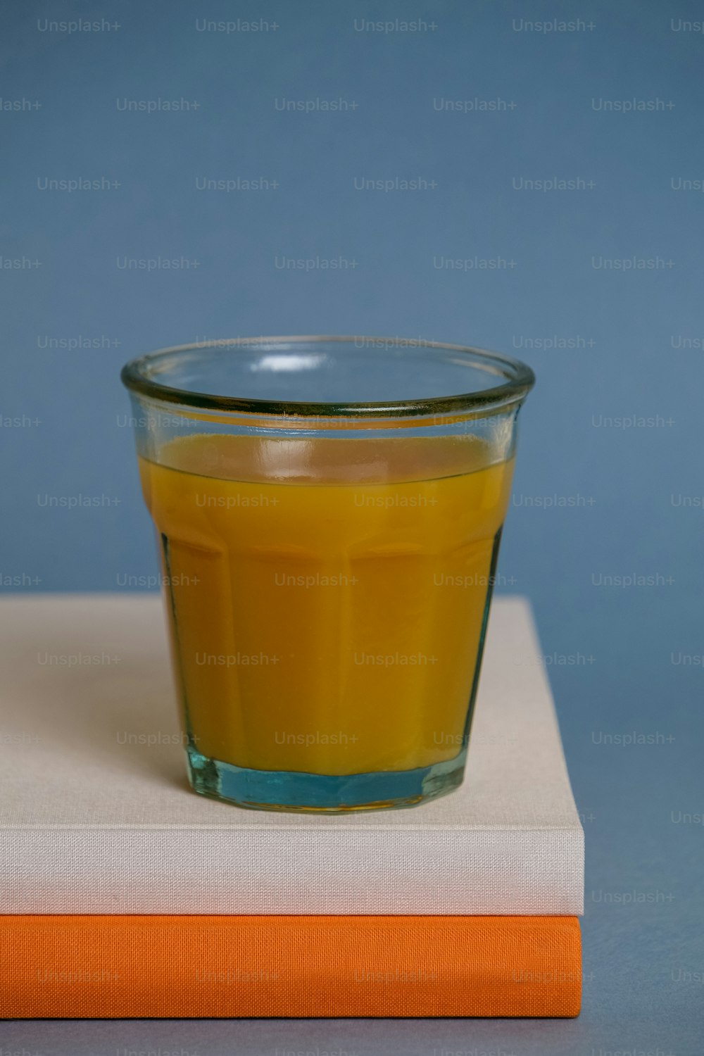 a glass of orange juice sitting on top of a book