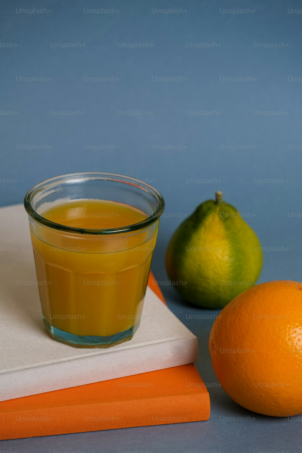 ein Glas Orangensaft neben einer Orange und einem Buch