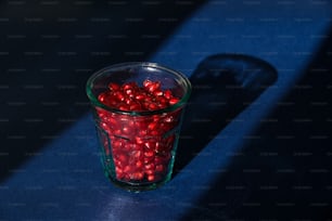 um copo cheio de doces vermelhos sentado em cima de uma mesa