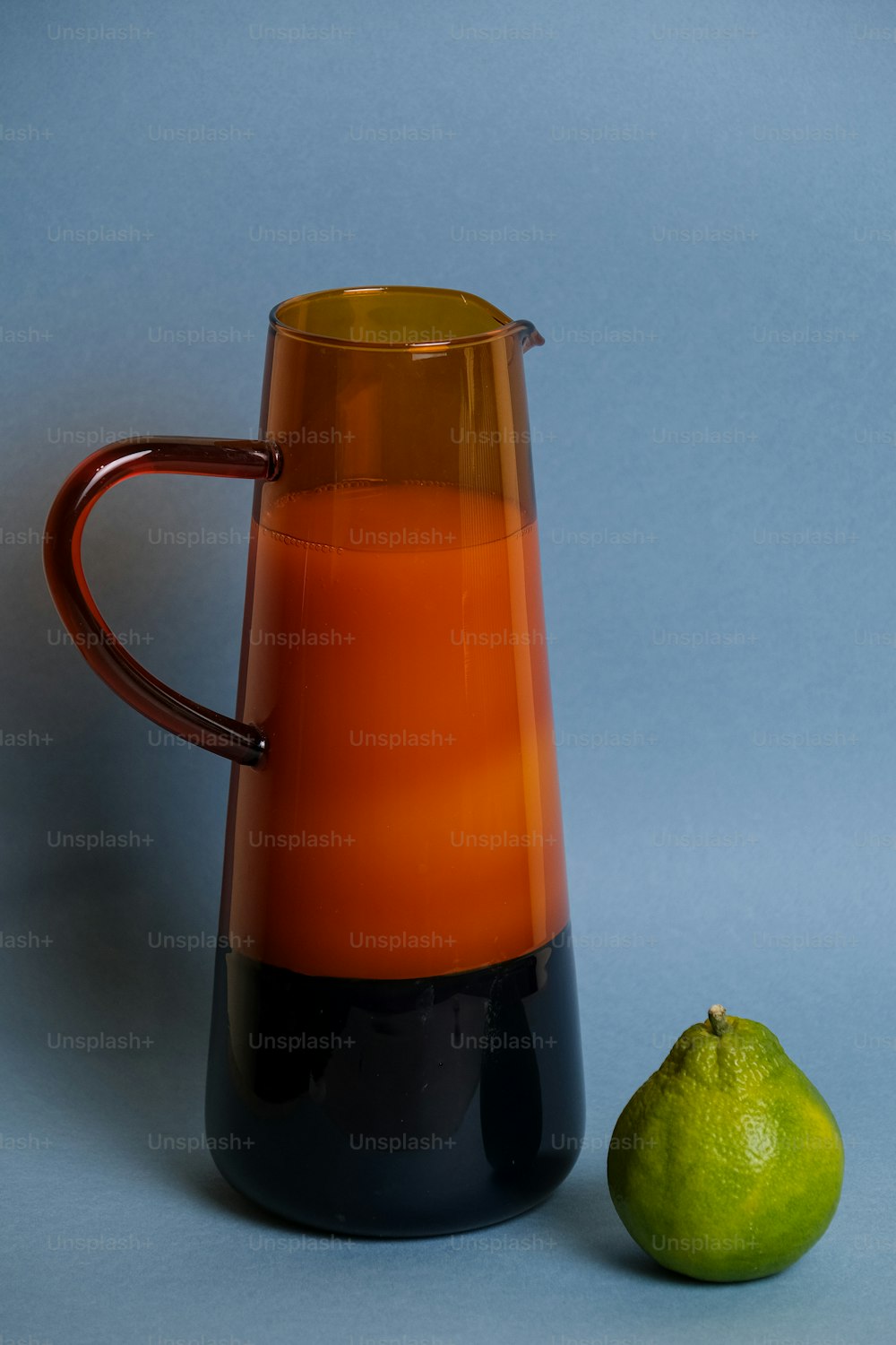 an orange and black pitcher next to a lime