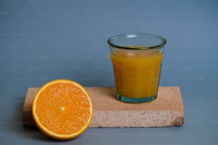 a glass of orange juice next to an orange slice