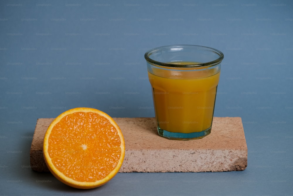 a glass of orange juice next to an orange slice