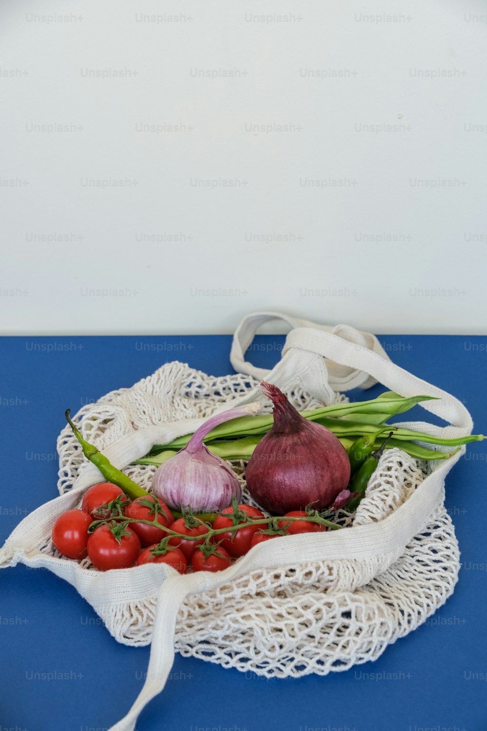 青いテーブルの上に野菜が入った白い袋