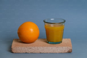 um copo de suco de laranja ao lado de uma laranja