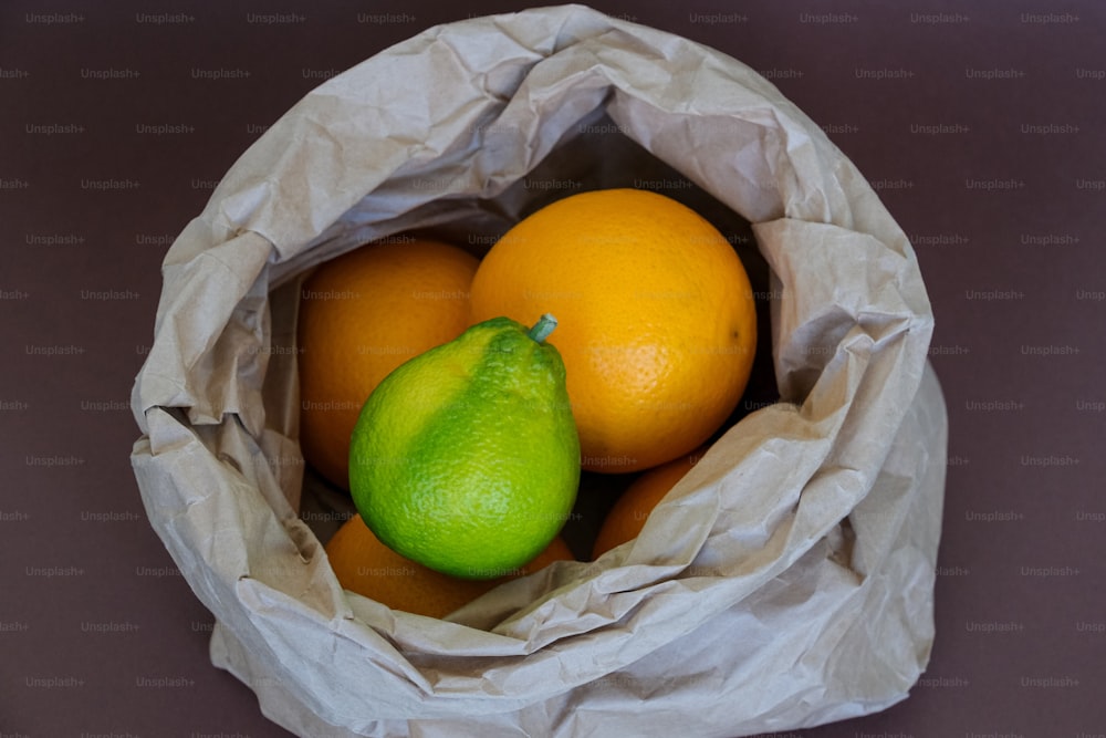 um saco de papel cheio de laranjas e uma pera