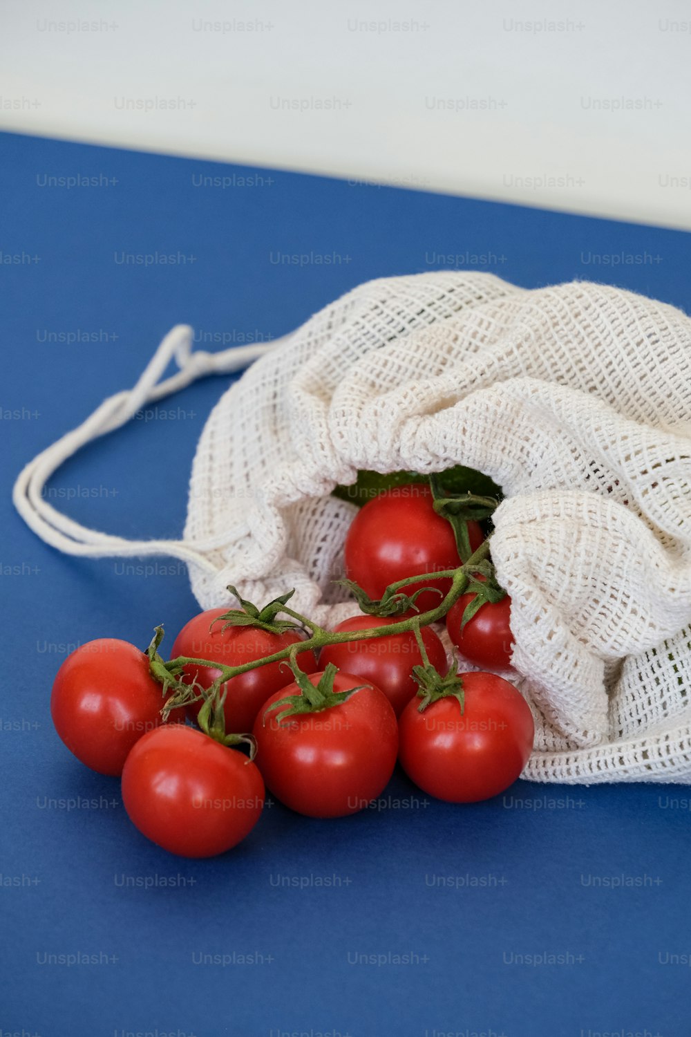 um saco de tomates em uma superfície azul