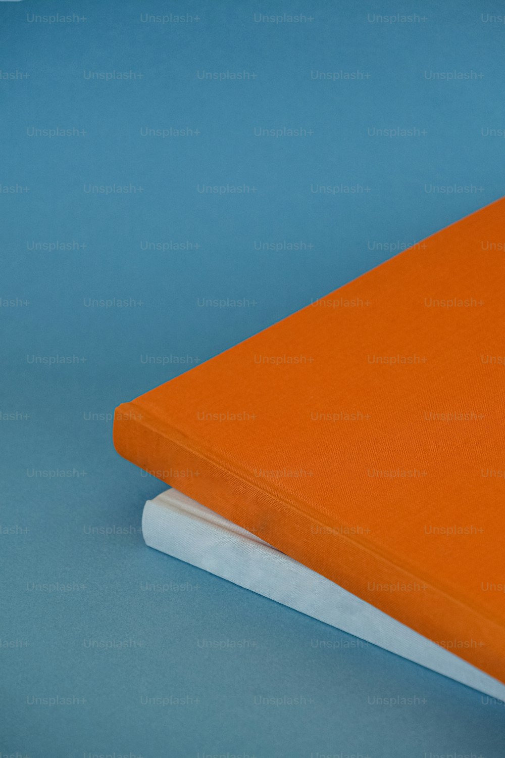Un quaderno arancione seduto sopra un libro bianco
