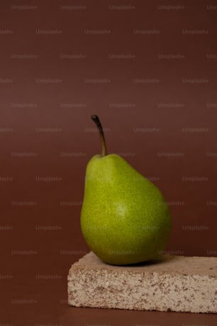 a green pear sitting on top of a stone block