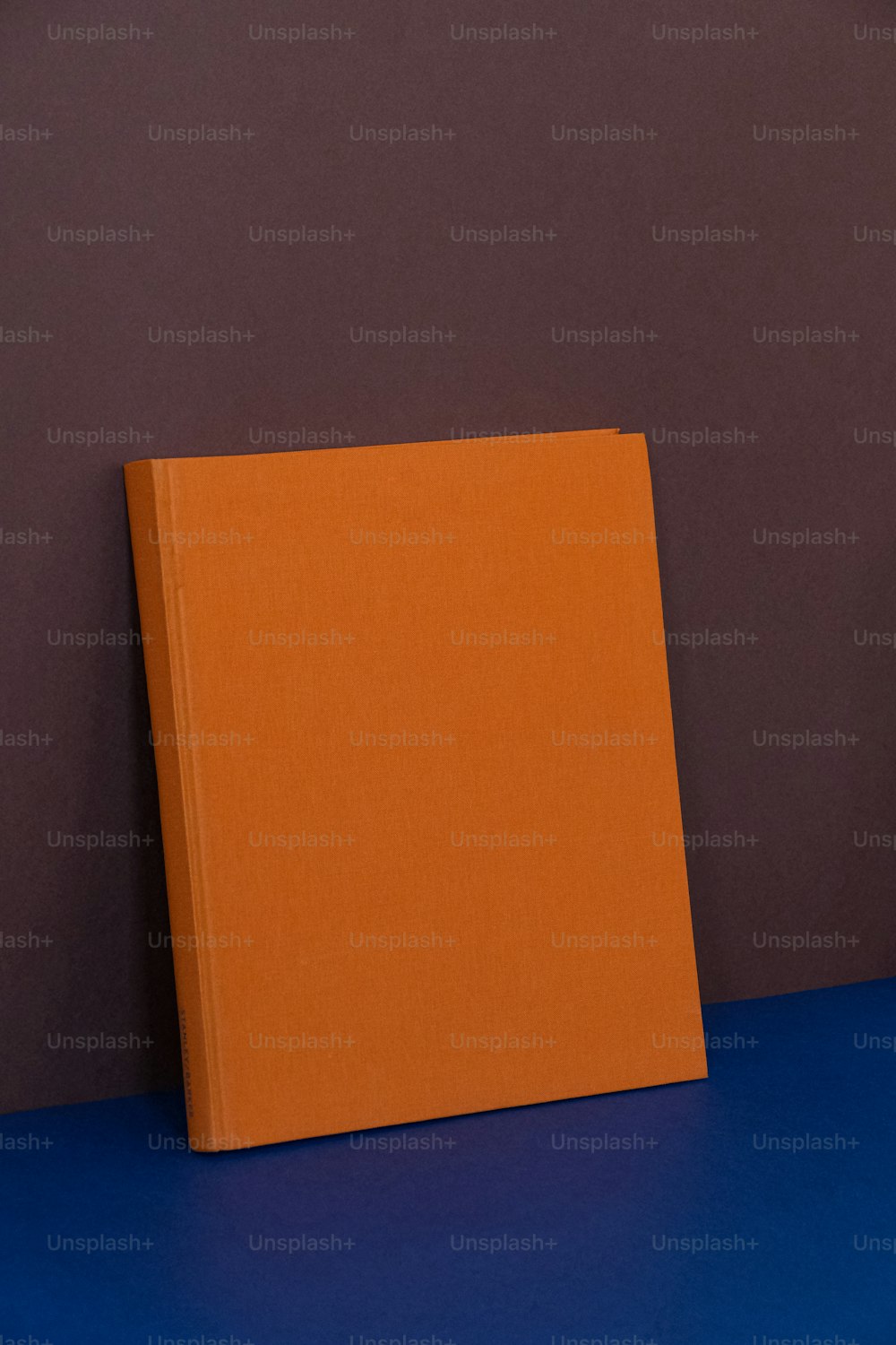 Un libro arancione seduto sopra un tavolo blu
