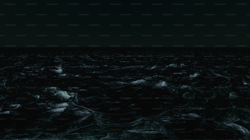 a black and white photo of the ocean at night