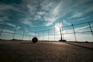 a basketball ball sitting on the ground in front of a fence