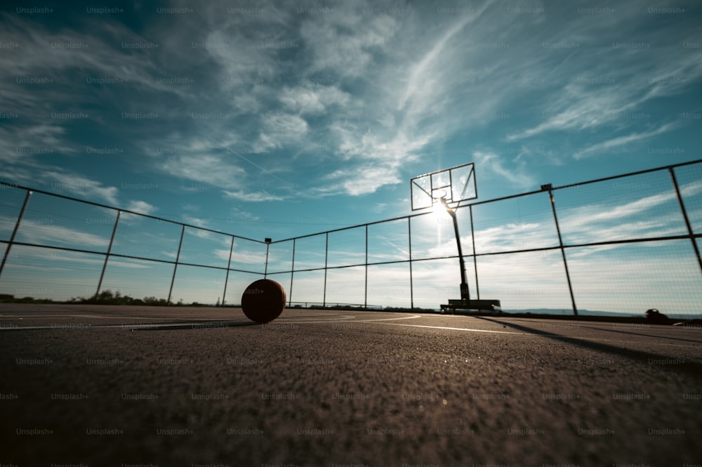 フェンスの前の地面に座っているバスケットボールのボール