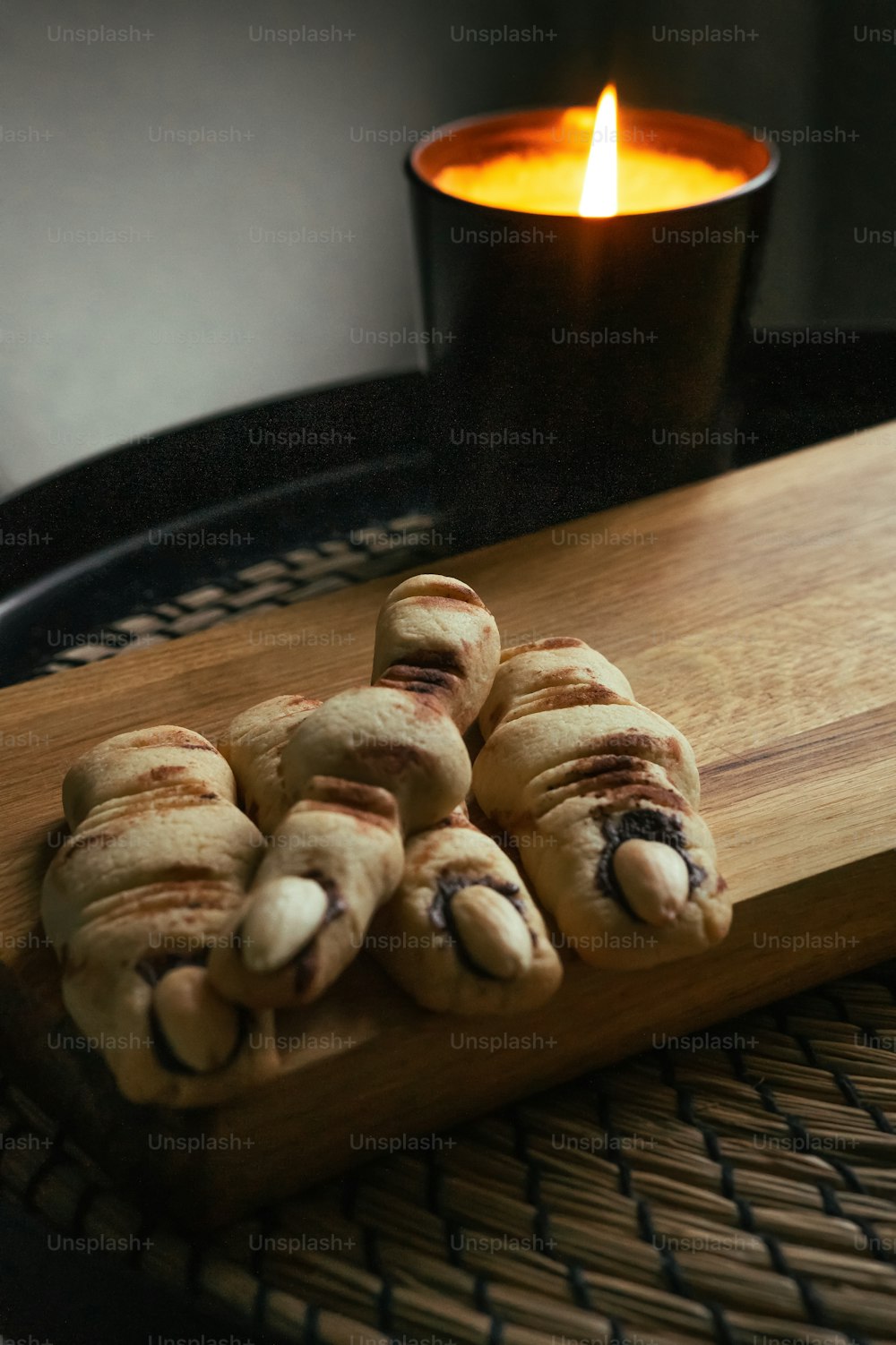 a wooden cutting board topped with cookies next to a lit candle