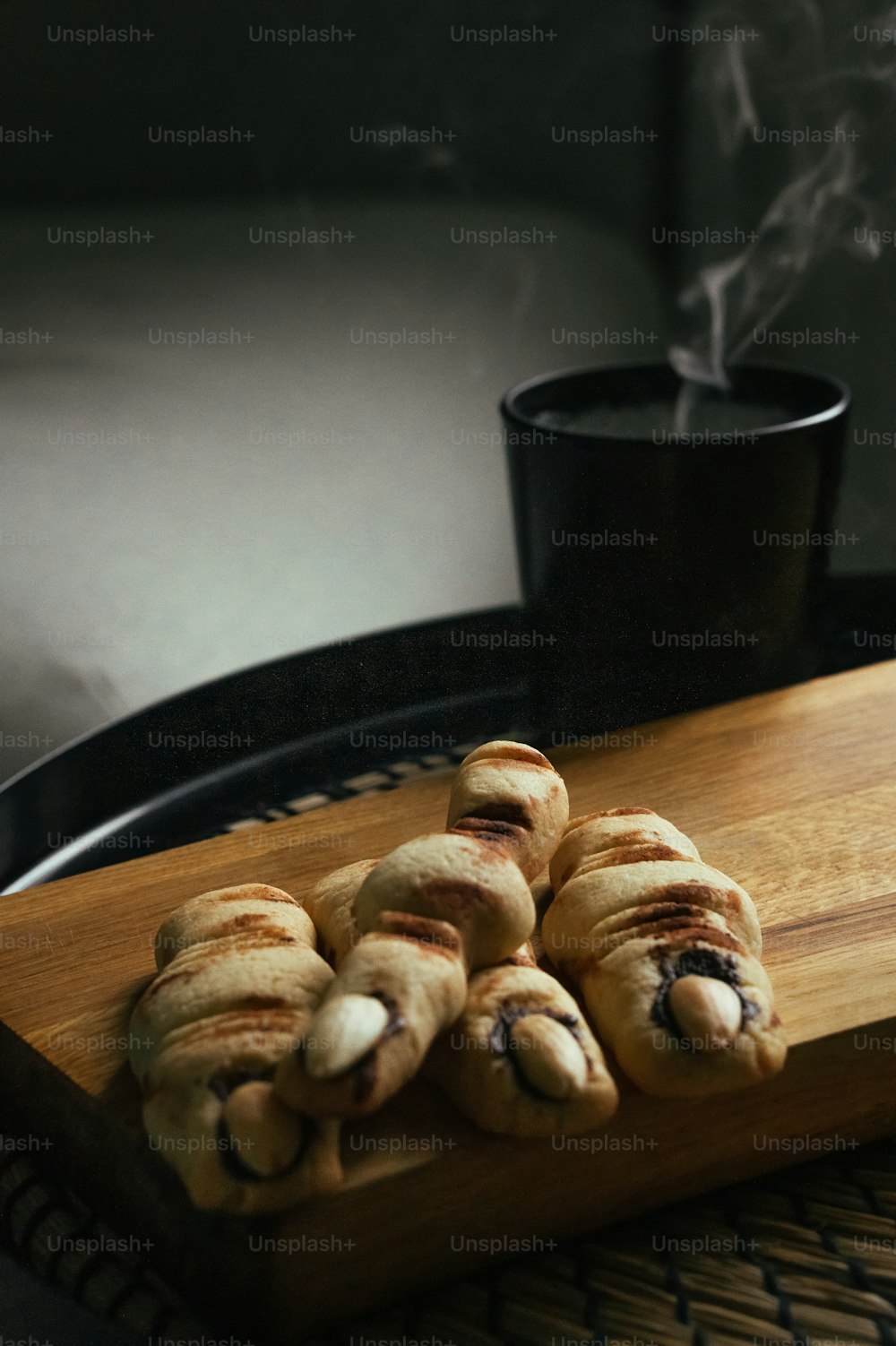 a wooden tray topped with pastries next to a cup of coffee