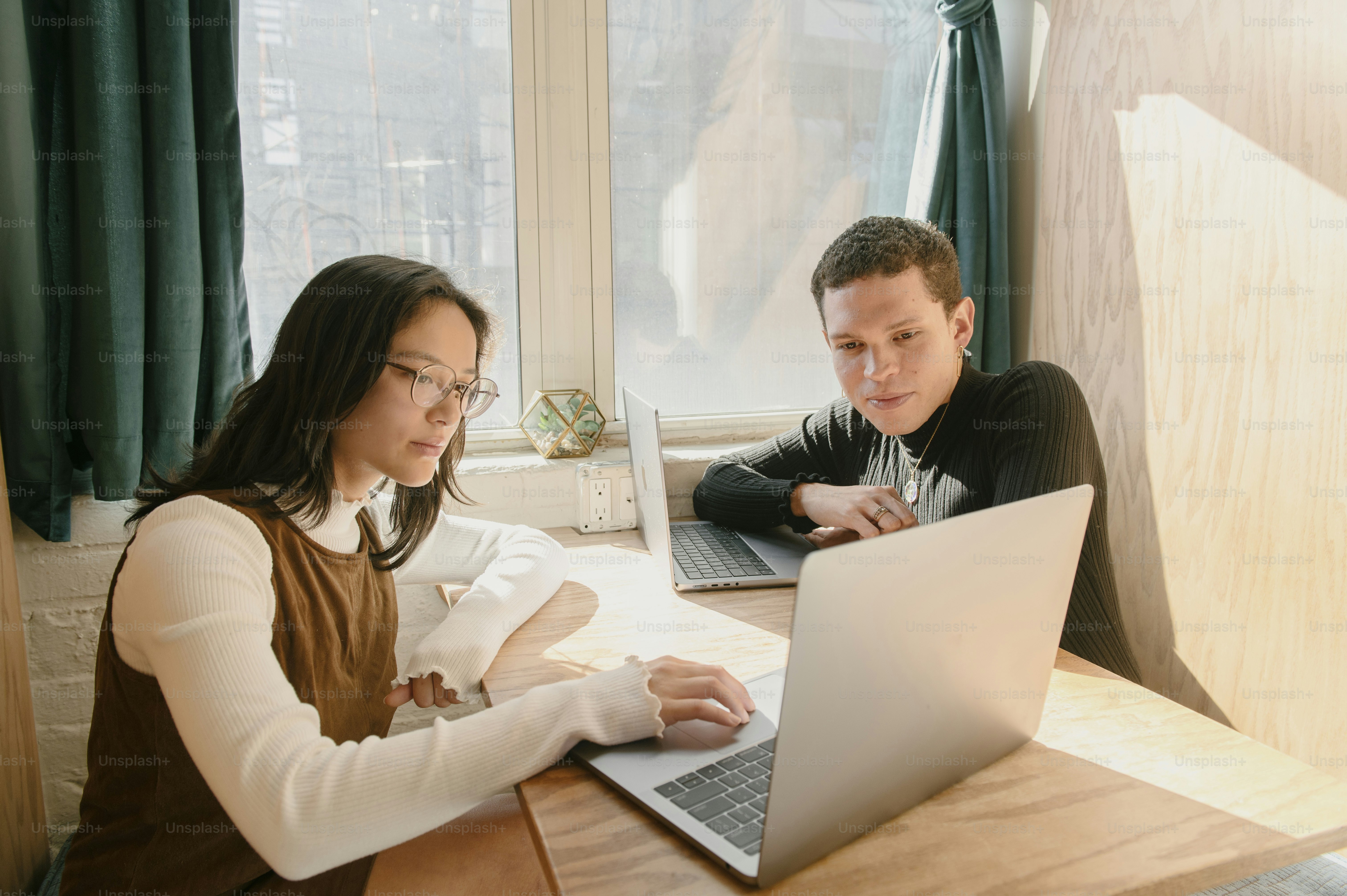 Un hombre y una mujer sentados en una mesa con una computadora portátil