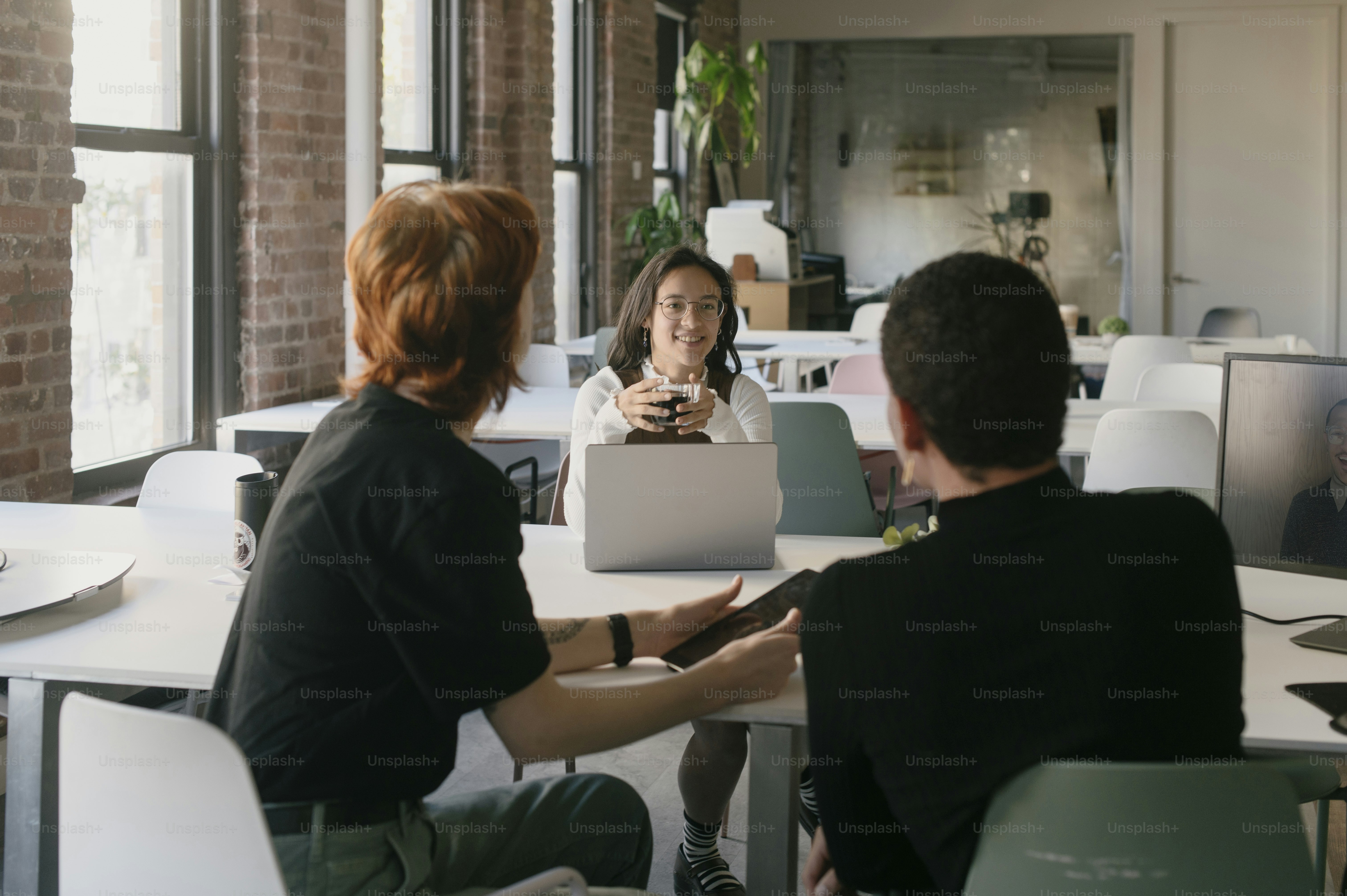 Un grupo de personas sentadas alrededor de una mesa con computadoras portátiles