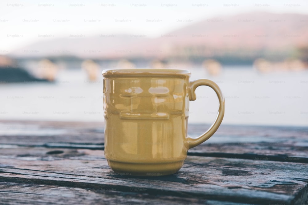 a yellow mug sitting on top of a wooden table