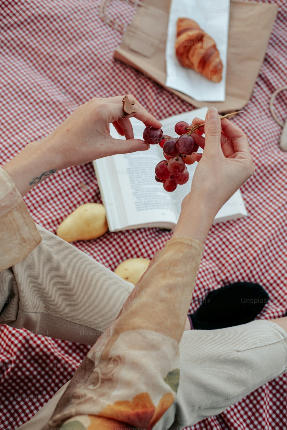 a woman sitting at a table with a book and grapes