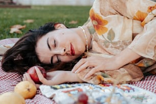 uma mulher deitada em um cobertor segurando uma maçã