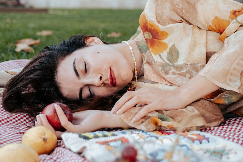 Eine Frau, die auf einer Decke liegt und einen Apfel hält
