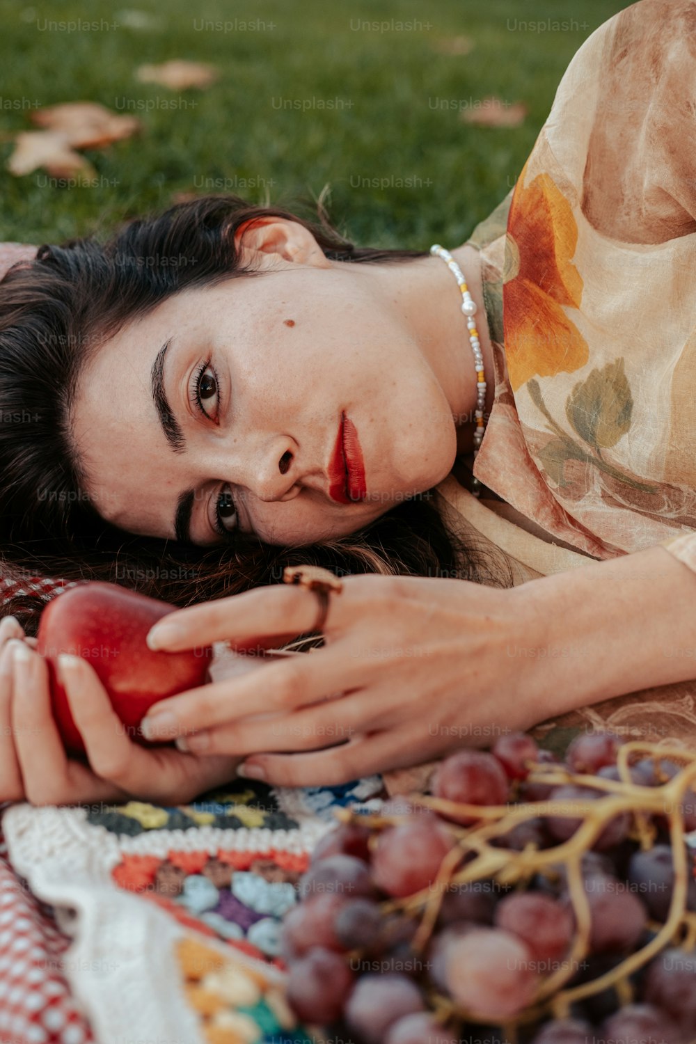 a woman laying on a blanket holding an apple