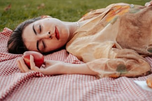 사과를 들고 담요 위에 누워 있는 여자