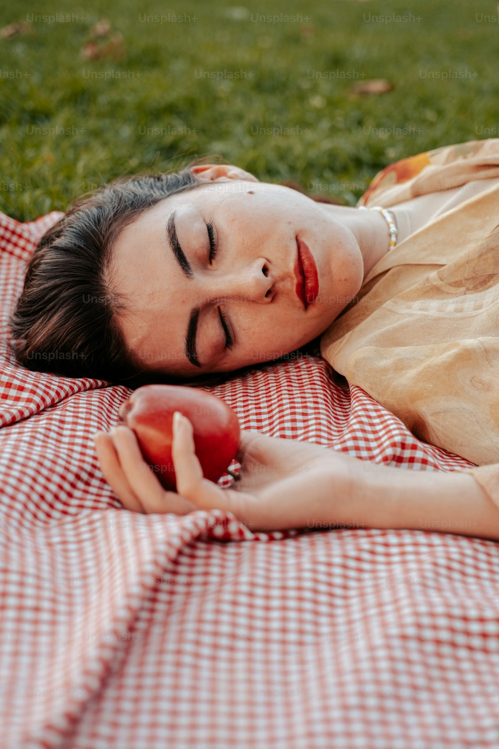 リンゴを持って毛布の上に横たわる女性