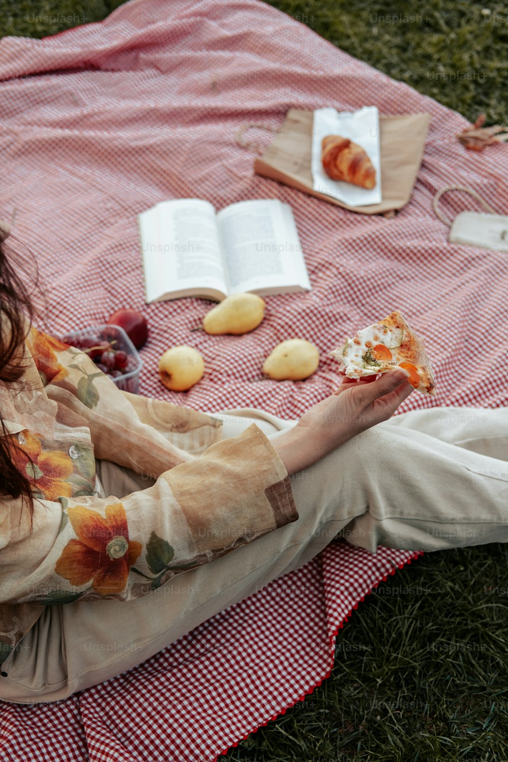 una donna seduta su una coperta che mangia cibo