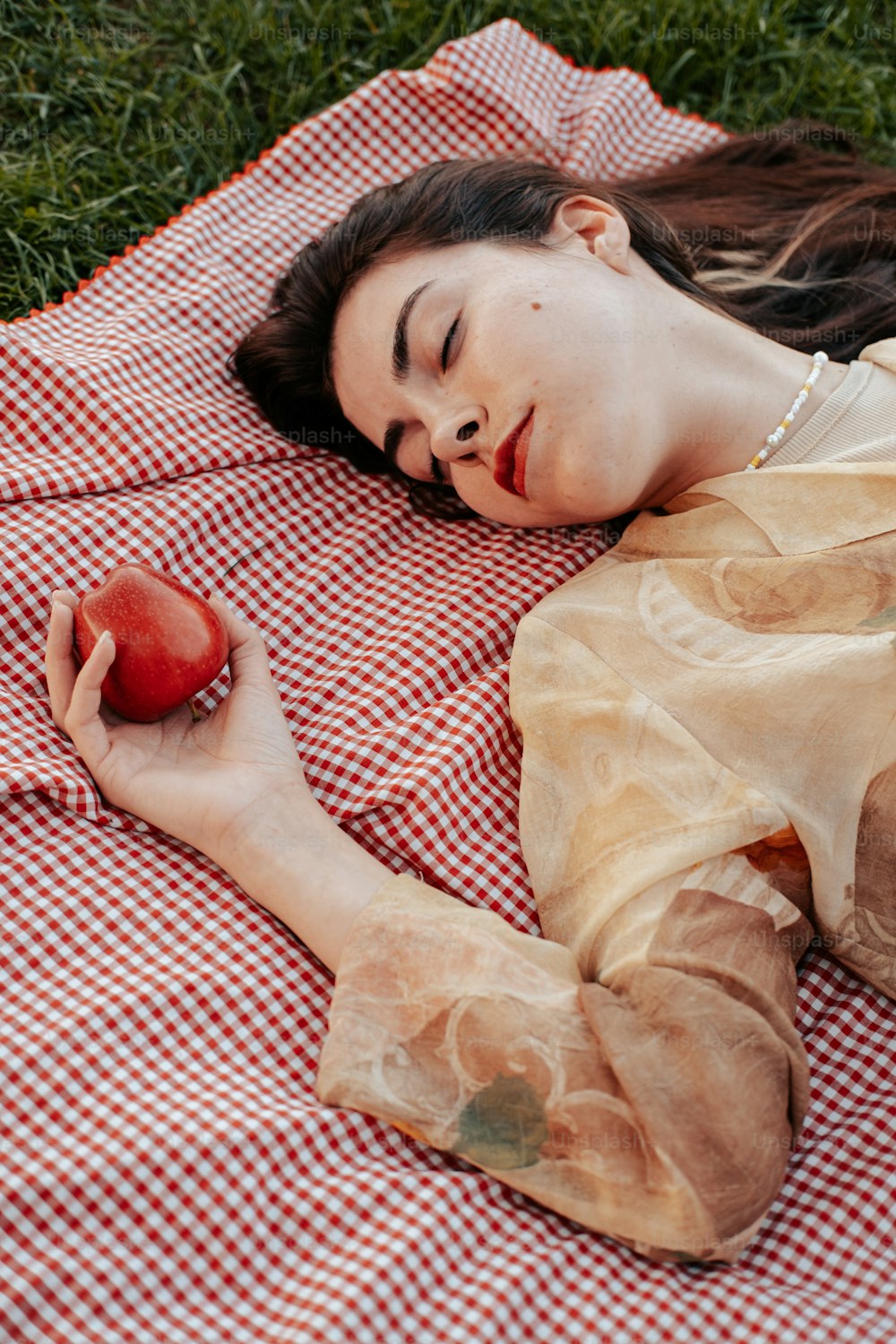 사과를 들고 담요 위에 누워 있는 여자