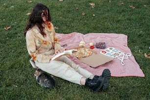 a woman sitting on a blanket in the grass