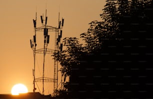 the sun is setting behind a cell tower