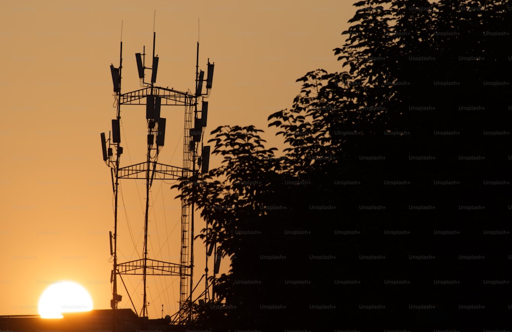 the sun is setting behind a cell tower