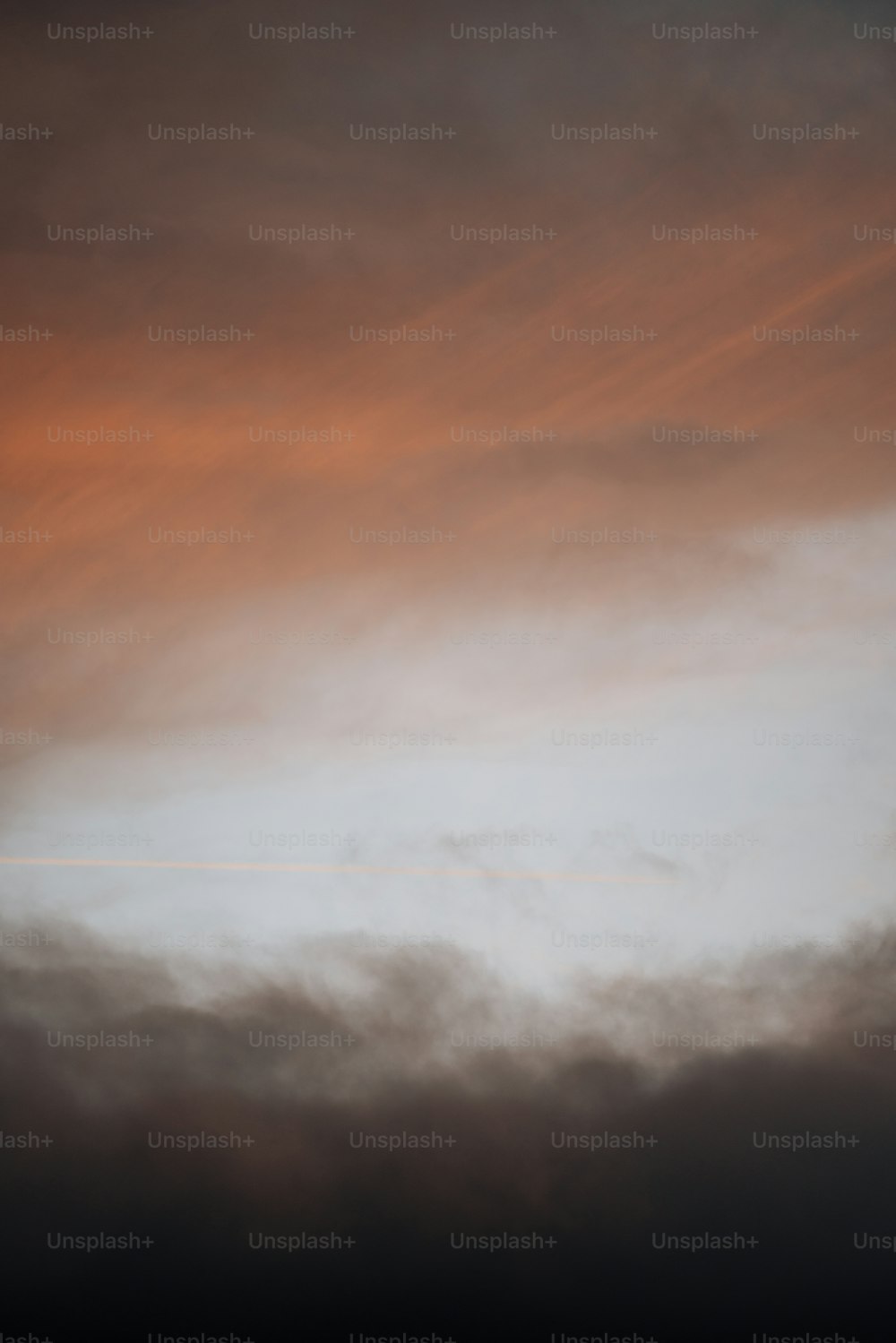 Un avion volant dans un ciel nuageux au coucher du soleil