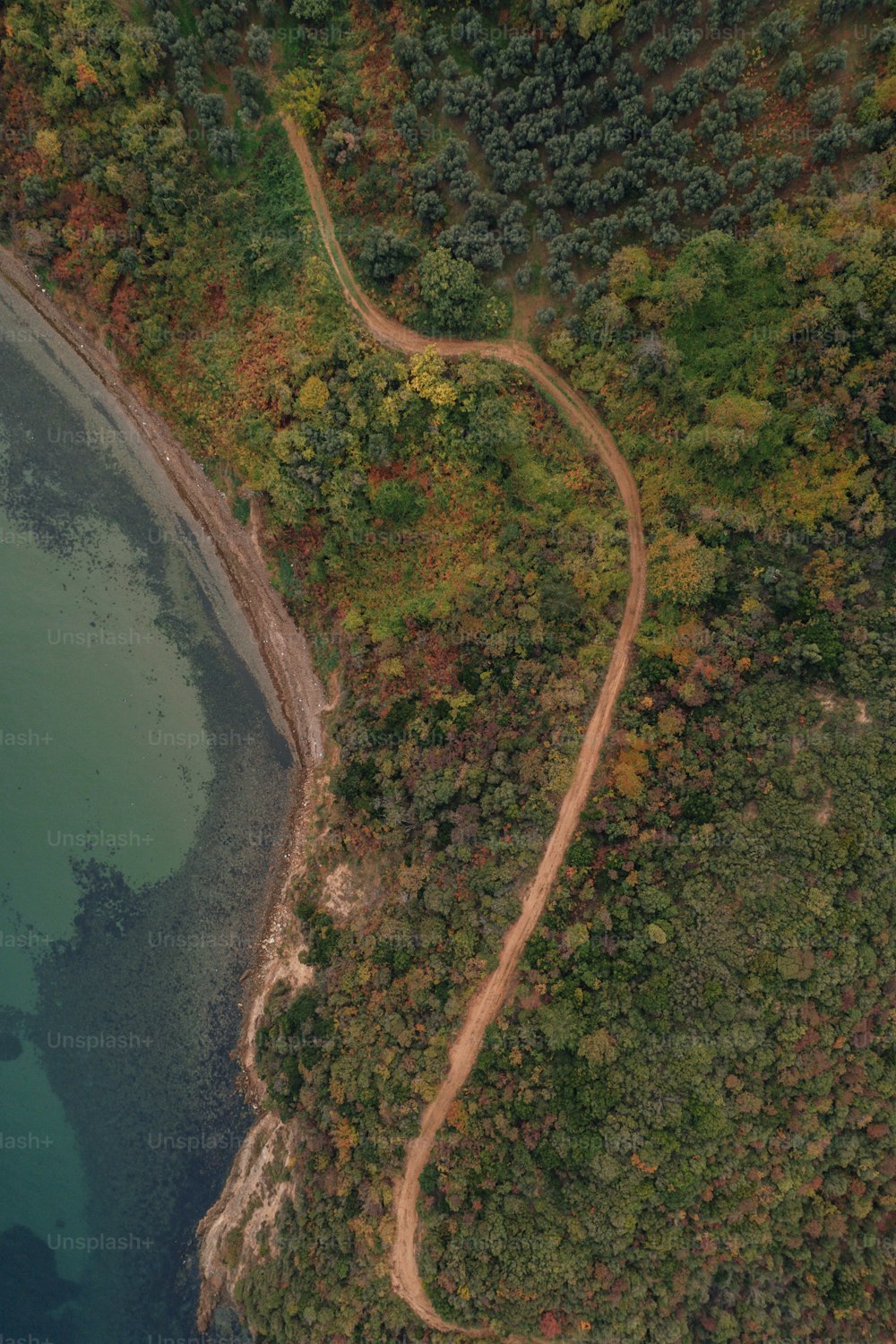 an aerial view of a winding road near a body of water