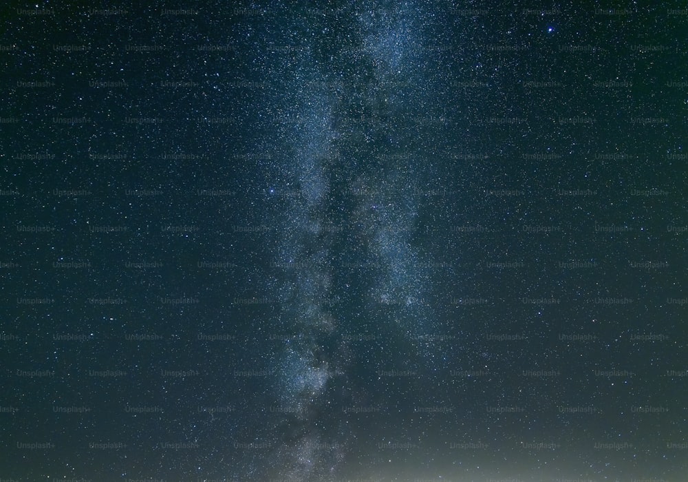 um grupo de pessoas em pé no topo de um campo sob um céu cheio de estrelas