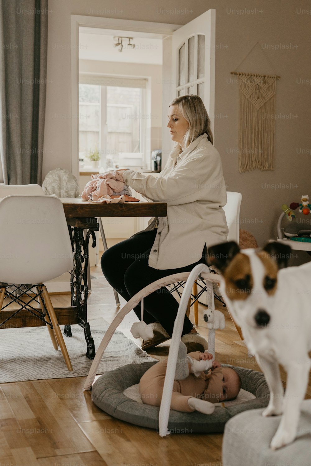 a woman sitting at a table with a baby and a dog