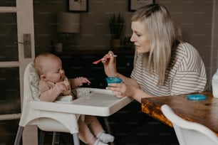 Eine Frau, die in einem Hochstuhl sitzt und ein Baby füttert