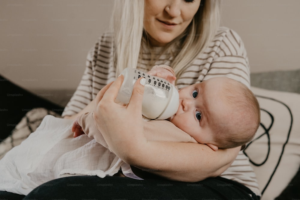 哺乳瓶を持ちながら赤ん坊を抱く女性