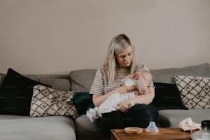 a woman sitting on a couch holding a baby