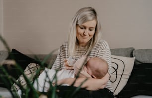 a woman holding a baby while sitting on a couch