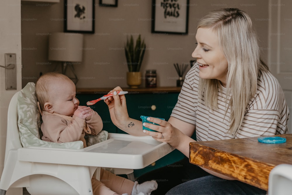 uma mulher está alimentando um bebê com uma escova de dentes