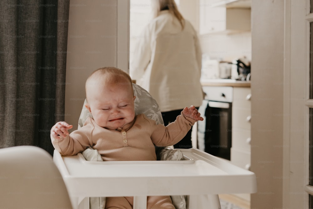 a baby crying while sitting in a high chair