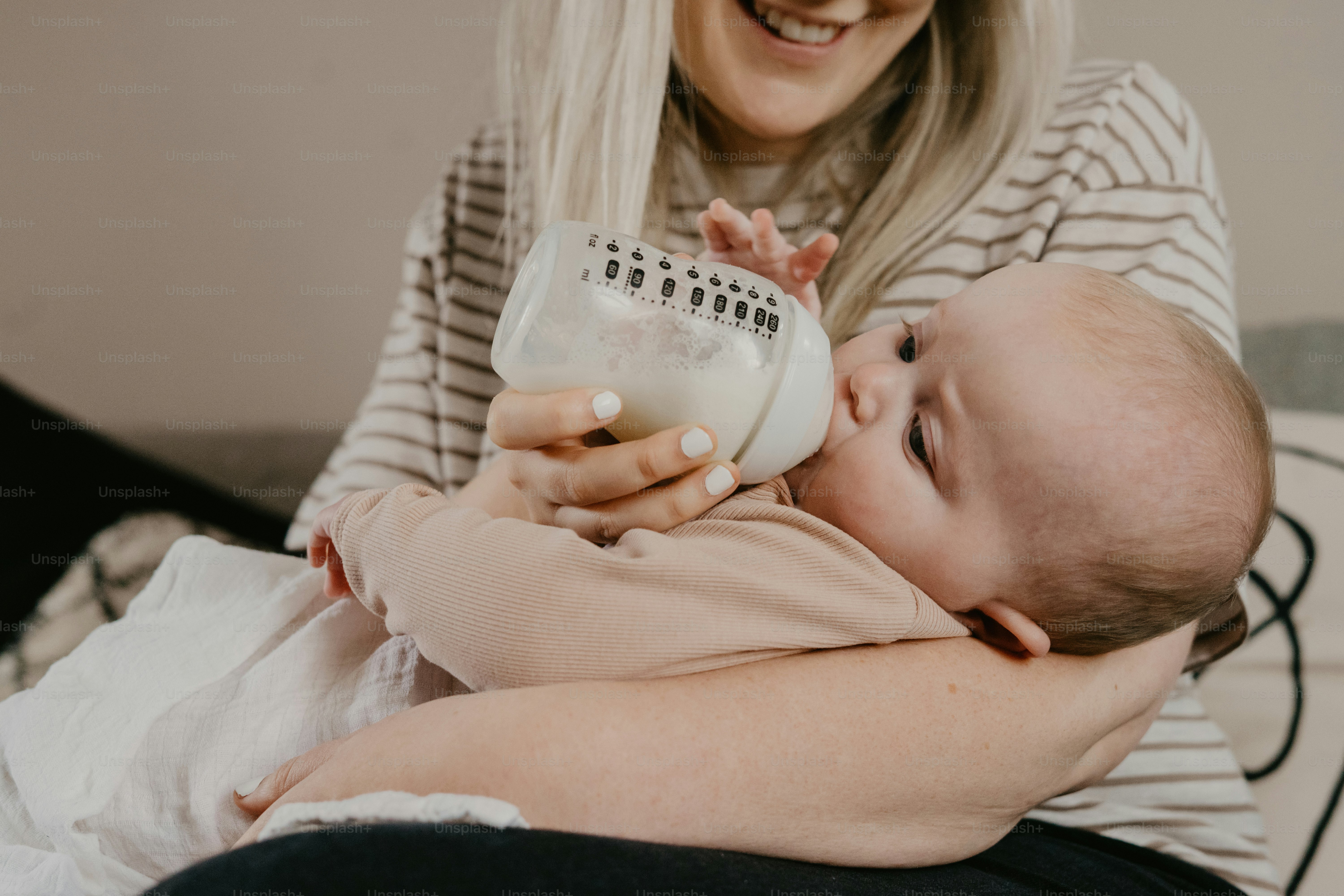 a woman holding a baby while holding a bottle