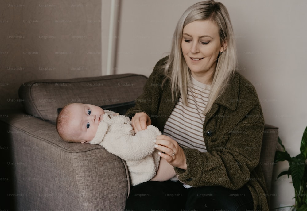 a woman sitting on a couch holding a baby