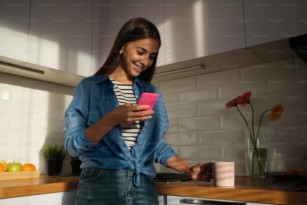 a woman standing in a kitchen holding a cell phone