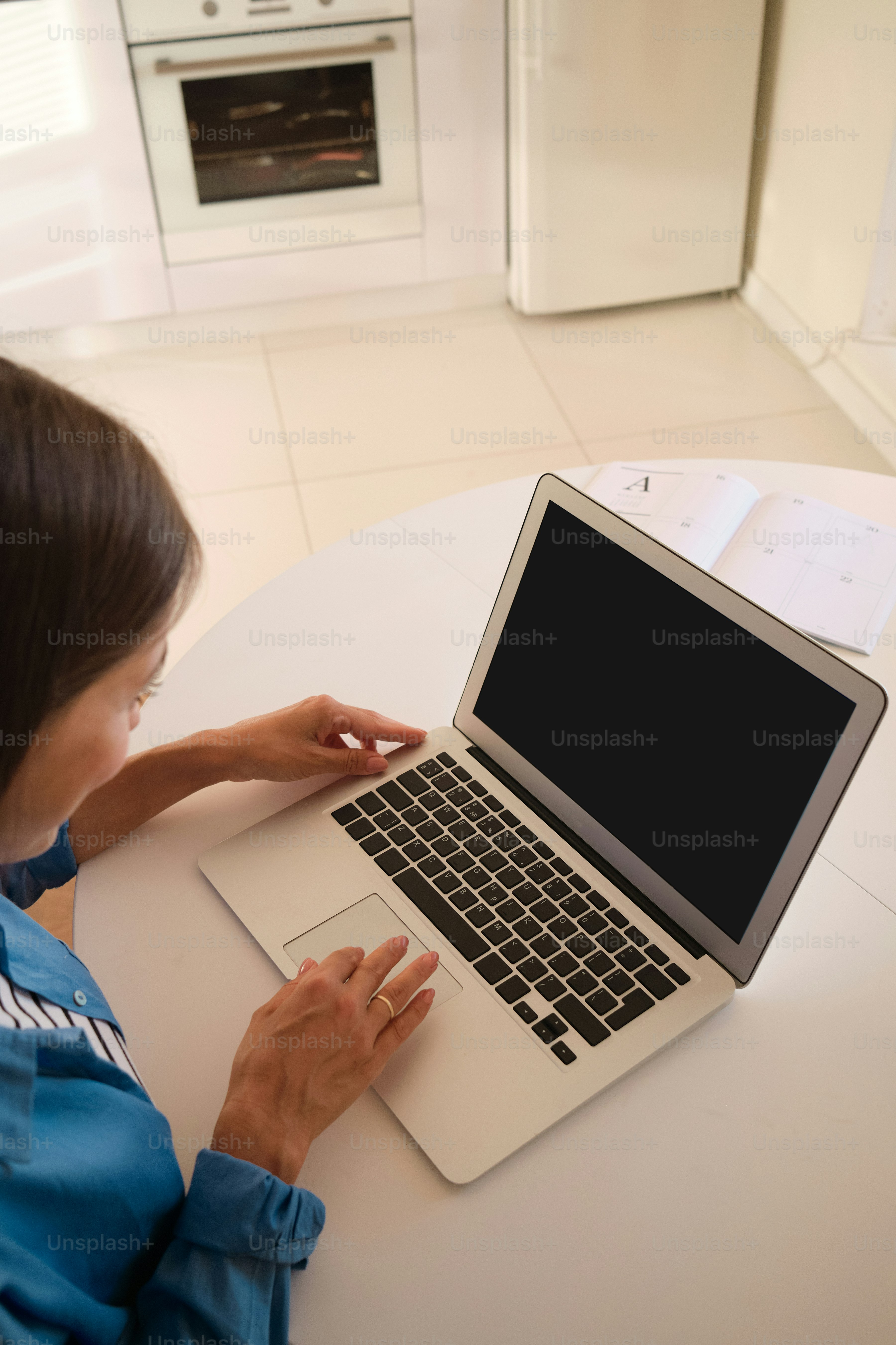 ノートパソコンを使ってテーブルに座る女性